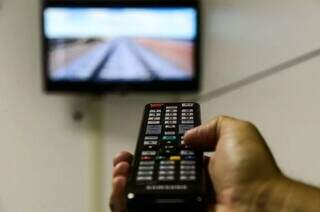 Homem segura controle para ligar televisão (Foto: Arquivo/Campo Grande News)