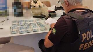 Policial federal contando dinheiro encontrado com investigados (Foto: Divulgação | PF)