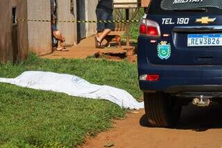 Corpo da vítima coberto por lençol ao lado da viatura da Polícia Militar (Foto: Henrique Kawaminami)