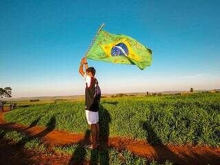 Jovem indígena protesta com bandeira do Brasil, em área de disputa agrária em Mato Grosso do Sul (Foto: Iara Cardoso)