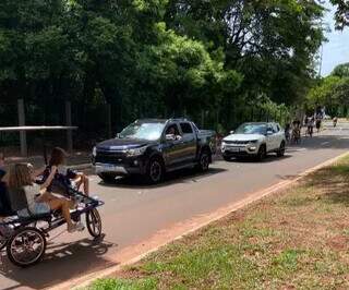 Família em triciclo disputa espaço com veículos em avenida do Parque dos Poderes.