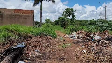Lixo em terreno baldio invade rua sem asfalto no Guanandi