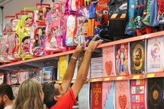 Vendedor de loja pega mochila para mostrar a consumidora (Foto: Henrique Kawaminami) 