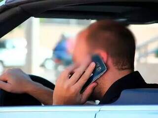 Homem fala ao celular enquanto dirige (Foto: Arquivo / Campo Grande News)