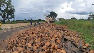 Carga de tijolos espalhada na pista e carreta com carroceria aberta (Foto: Nova News)