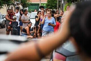 Mãe do adolescente sentada em uma cadeira sendo consolada por vizinha (Foto: Henrique Kawaminami)