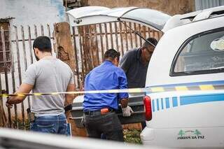 Agentes funerários recolhendo o corpo da vítima (Foto: Henrique Kawaminami) 