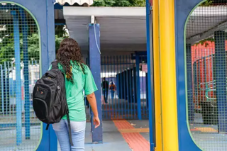 Aluna com mochila nas costas entra em escola estadual em Campo Grande (Foto: Henrique Kawaminami)