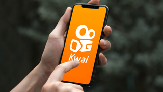 Tela do aplicativo Kwai em um celular segurado por uma pessoa (Foto: Ilustrativa)