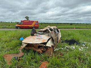 Carro destruído e corpo coberto ao lado do veículo às margens da rodovia (Foto: Elisan Ramos | Cenário MS)