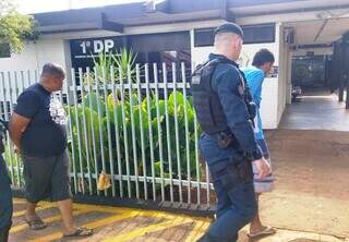 Policiais conduzem os dois presos em entreposto do tráfico, ontem, em Dourados (Foto: Adilson Domingos)