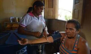 Agente comunitária de saúde mede pressão de assistida em casa. (Foto: Marcello Casal Jr./Agência Brasil)