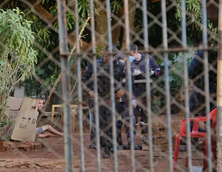 No canto esquerda da foto, o autor algemado e sentado no chão. Do outro lado, o corpo da vítima caído no quintal. (Foto: Arquivo/Campo Grande News)