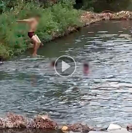 Crianças tomam banho animados em rio, no vai e vai da Ernesto Geisel  