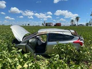 Ford Focus na plantação de soja e equipes do Corpo de Bombeiros na rodovia (Foto: A Gazeta News)
