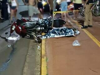 Motos destruídas após batida e corpo da vítima coberto. (Foto: Ponto da Notícia)
