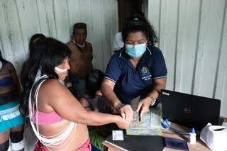 Servidora da Justiça Eleitoral realizando cadastro em aldeia (Foto: Antonio Augusto/TSE)