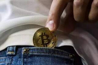 Pessoa segura moeda figurativa, que representa a criptomoeda &#34;bitcoin&#34; (Foto: Arquivo/Worldspectrum)