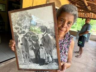 Adesuíta Correia mostra a foto do pai e com os dois bois que auxiliam na lida diária no cultivo da mandioca (Foto: Marcos Maluf)