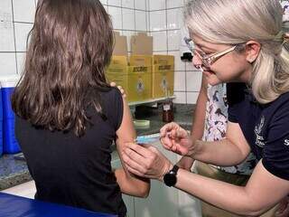 Secretária de Saúde da Capital, Rosana Leite, aplica primeira dose da vacina contra a dengue em Lorena Cintra, de 10 anos. (Foto: Marcos Maluf)