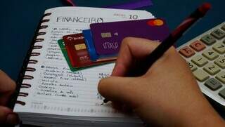 Pessoa calcula dívidas de cartões de crédito do mês (Foto: Alex Machado)