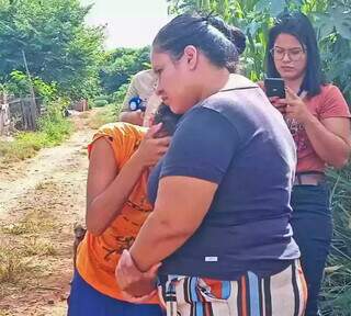 Adolescente de 16 anos, (de blusa laranja) enquanto era consolada pela vizinha (Foto: Idaicy Solano)