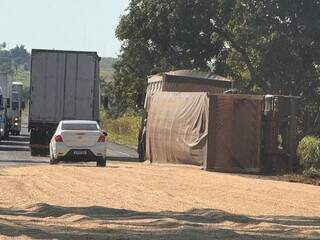 Carga de soja espalhada na pista e semirreboque tombado na rodovia (Foto: Nova News)