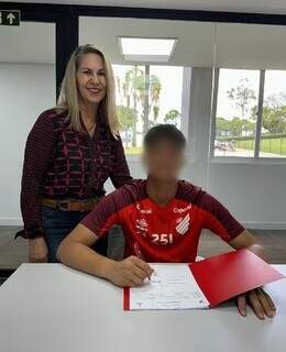 Bruninho assinando contrato com o Athletico Parananense na companhia da avó, Sônia Moura (Foto: Jornal Extra/Divulgação)