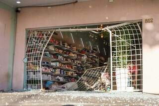 Grade e porta da loja ficaram totalmente destruídas; pelo chão cacos de vidro estão espalhados (Foto: Henrique Kawaminami)