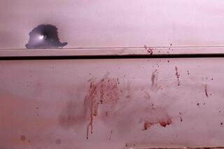 Sangue e marca de tiro no portão de uma residência (Foto: Juliano Almeida)
