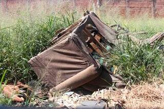 Sofá e restos de materiais de construção jogados em terreno (Foto: Marcos Maluf)