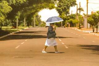 Mulher caminhando com sombrinha para se proteger do sol quente (Foto: Marcos Maluf)
