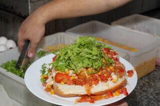 Processo de montagem do hot dog que leva mais de cinco ingredientes. (Foto: Juliano Almeida)