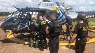Cercado por policiais, &#34;Tonho&#34; (de branco) embarca em helicóptero após prisão. 