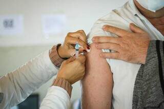 Profissional da saúde aplicando vacina em homem (Foto: Henrique Kawaminami) 