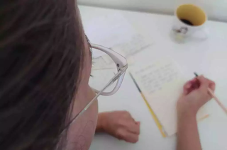 Estudante de óculos escreve uma carta de próprio punho. (Foto: Arquivo/Campo Grande News)