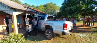 Policiais ao lado da caminhonete que invadiu casa após condutor ser alvejado por pistoleiros (Foto: ABC Color)