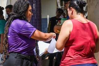 Ladielly, de camiseta roxa, entregando panfleto para mãe de aluno (Foto: Henrique Kawaminami)