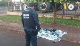 Policial ao lado do corpo e João Paulo de Souza; rapaz morto com seis facadas (Foto: Leandro Holsbach)