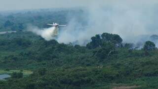 Avião despejando água em área com fogo ativo para tentar minimizar propagação do incêndio (Foto: Semadesc)