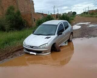 Roda de veículo torta após cair em buraco de rua alagada, no bairro Recanto do Cerrado (Foto: Direto das Ruas)