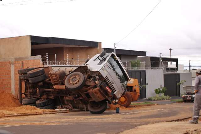 Caminh&atilde;o ca&ccedil;amba carregado de areia tomba e atinge carro