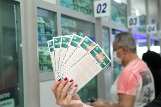 Apostadora segura volantes de aposta da Mega-Sena em agência lotérica da Capital. (Foto: Arquivo/Campo Grande News)