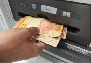 Pessoa saca cédulas de dinheiro em caixa eletrônico. (Foto: Arquivo)