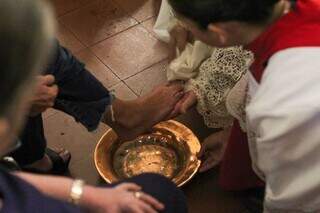 Sacerdote lava o pé de fiel durante celebração cristão em Campo Grande. (Foto: Juliano Almeida)