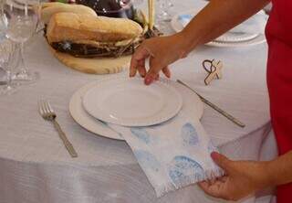 Outra forma de arrumar o guardanapo é deixar o tecido entre os pratos. (Foto: Paulo Francis)