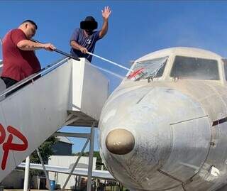 De camiseta vermelha, Carmo Name, que já foi dono de lava a jato, limpa avião. (Foto: Redes Sociais)