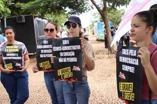 Manifestantes do IFMS e UFMS seguram cartazes na Orla do Aeroporto (Foto: Paulo Francis)
