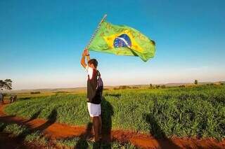 Jovem indígena protesta com bandeira do Brasil, em área de disputa agrária em Mato Grosso do Sul (Foto: Iara Cardoso/Arquivo)