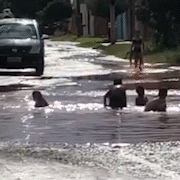 Crianças transformam em “lagoa” cratera aberta no meio da rua 
